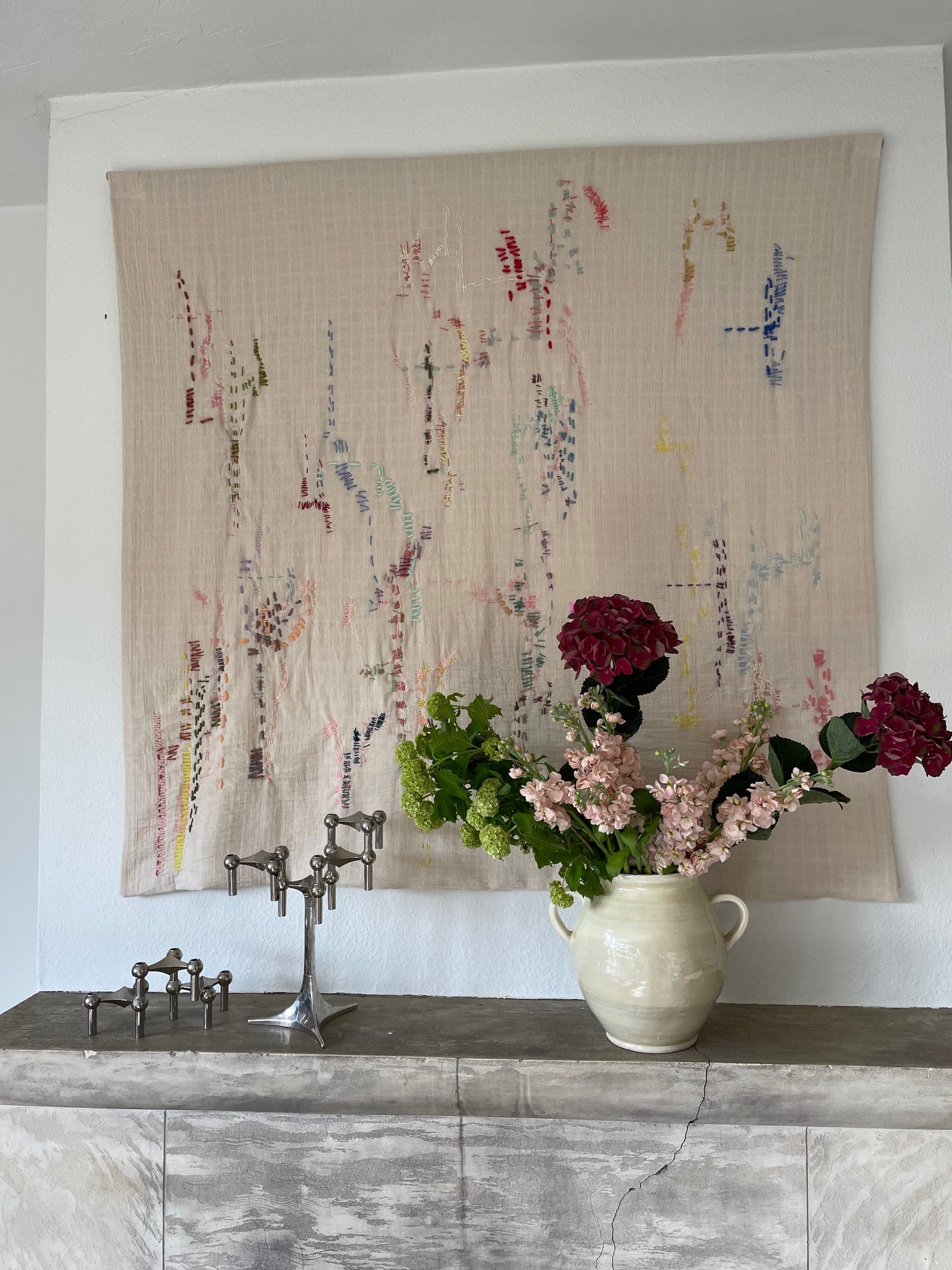 Helen - Handcrafted Wall Hanging , hand embroidered 130x130 cm, displayed on a wall above a fireplace